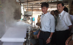 Ông Dương Minh Điều cùng các thành viên trong đoàn đến tìm hiểu hoạt động của một số cơ sở sản xuất bánh tráng trong làng nghề. Ảnh NGÔ TÔNG