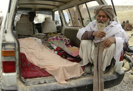 Người đàn ông Afghanistan ngồi bên cạnh xác những người trong vụ thảm sát 16 dân thường ở tỉnh Kandahar vào ngày 11-3 vừa qua