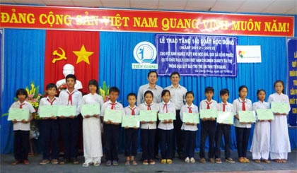 Ông Hồ Thanh Sơn, Chủ tịch Quỹ Bảo trợ trẻ em tỉnh và ông Trần Quốc Thanh, đại diện tổ chức Paul’s Kid trao học bổng và tập cho học sinh.