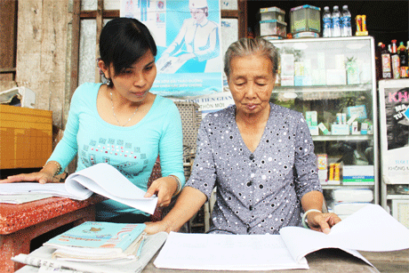 Bà Ba  và chị Nguyễn Thị Kim Hồng, cán bộ DS-KHHGĐ xã rà soát lại các  đối tượng cần  vận động và  phát thuốc miễn phí cho  người dân tại Tổ y tế sơ cấp cứu.