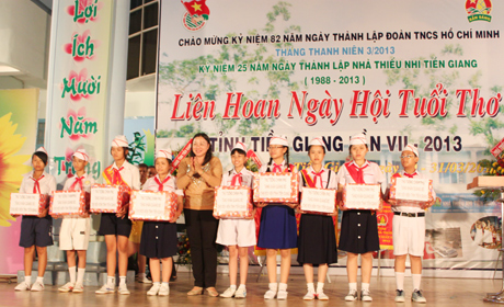 Bà Trần Kim Mai, Phó Chủ tịch UBND tỉnh trao khăn quàng đỏ  do Thủ tướng Chính phủ tặng thiếu nhi Tiền Giang.