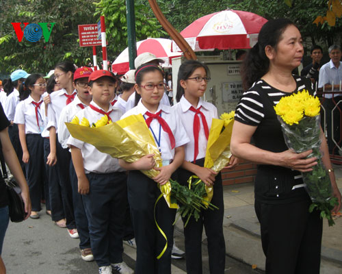 Học sinh đeo khăn quàng đỏ, tay cầm những bông hoa trang trọng vào viếng Đại tướng