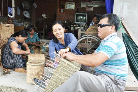 Chị Riếp hướng dẫn anh thương binh mù Nguyễn Văn Sáu thực hiện sản phẩm.