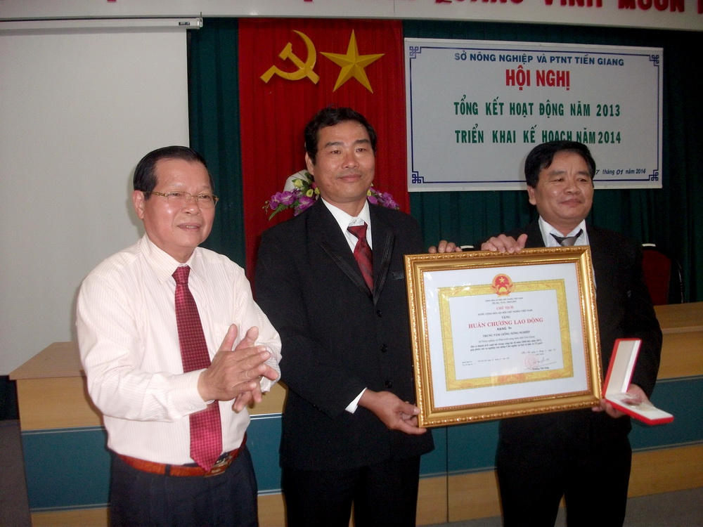 Chủ tịch UBND tỉnh Nguyễn Văn Khang trao Huân chương Lao động hạng Ba của Chủ tịch nước cho Trung tâm Giống nông nghiệp.