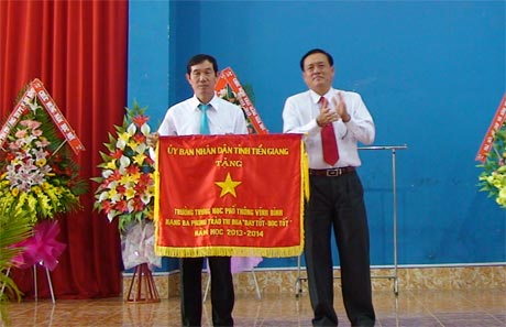 Ông Lê Văn Nghĩa, Phó Chủ tịch UBND tỉnh trao Cờ thi đua hạng Ba cho Trường THPT Vĩnh Bình.