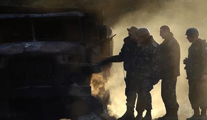Quân đội Ukraine bên cạnh một chiếc xe quân sự bị cháy ngày 7-9. Ảnh: AFP