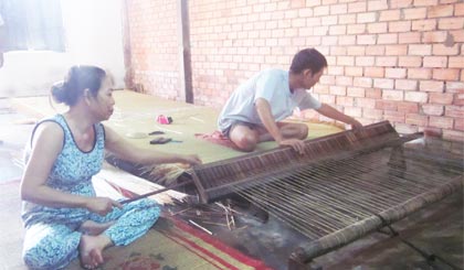 Gia đình anh Việt đang dệt chiếu truyền thống bằng thủ công.