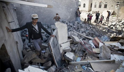 Người dân Yemen bên những ngôi nhà đổ nát. Ảnh: AP