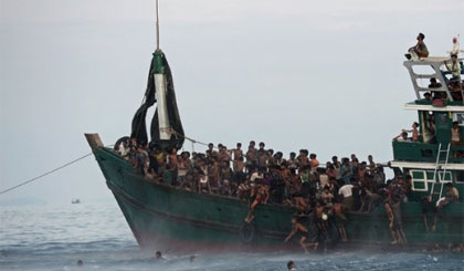 Người di cư Rohingya bơi ra để nhận đồ ăn cứu trợ trực thăng quân đội Thái Lan thả xuống biển Andaman hôm 14-5. Ảnh: AFP