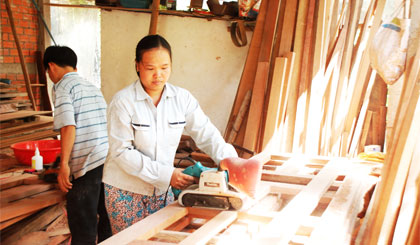 Chị Phạm Thị Thúy Hoa phụ chồng thực hiện công đoạn làm láng gỗ.
