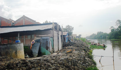 Nhà ông Trần Văn Bơ chưa bị giải tỏa theo chỉ giới, mà còn được công nhân công trình đào đất dưới kinh đắp xung quanh nhà.   