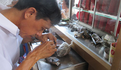 Chú Trần Văn  Đặng đang sửa đồng hồ cho khách.