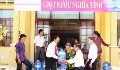 Ông Phan Văn Nghiệp - Phó Giám đốc Ngân hàng Nông nghiệp và Phát triển Nông thôn Việt Nam chi nhánh Tiền Giang trao bình nước cho các gia đình