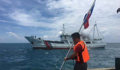 Một nhà hoạt động Philippines cắm cờ nước này trên tàu tại Bãi cạn Scarborough trước tàu Hải cảnh của Trung Quốc hôm 13-6. Nguồn: AFP