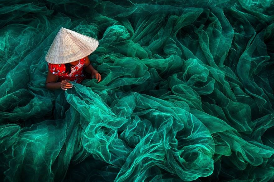 Đan lưới cá ở Phan Rang (Việt Nam) - Giải Nhất hạng mục ảnh màu: Bức ảnh được chụp ở một ngôi làng nhỏ gần Phan Rang (Việt Nam), nhân vật trong ảnh là một cô gái đội nón lá đang đan lưới thủ công. (Nguồn: boredpanda)