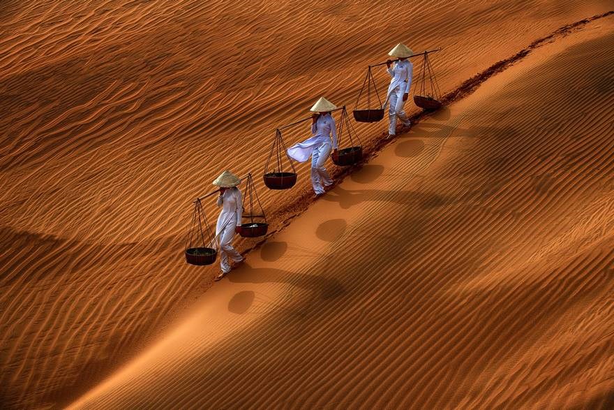 Đường nét và bóng người - Giải Danh dự hạng mục ảnh màu mở: Trên ụ cát ở Mũi Né, các cô gái đang đi dọc theo sườn cát, đội nón lá và tạo ra những đường nét tuyệt đẹp trên cát. (Nguồn: boredpanda)