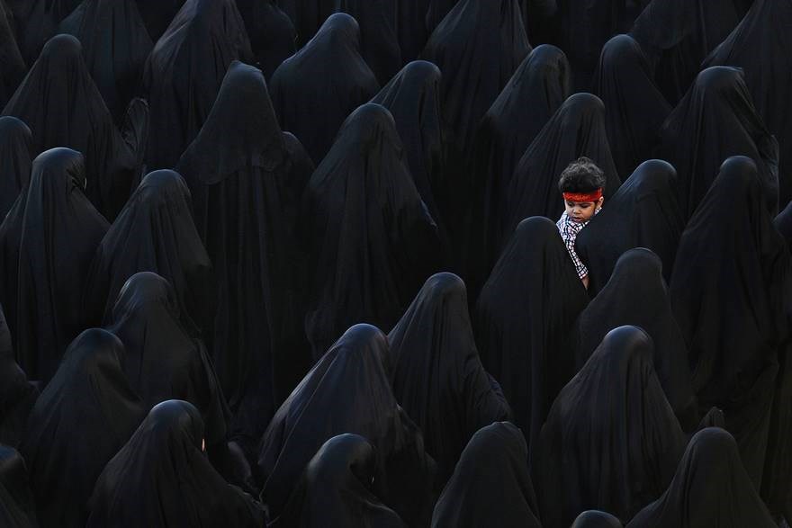 Tâm đen (Bahrain) - Giải Ba hạng mục ảnh màu mở: Một người phụ nữ Hồi giáo bế con trai giữa dòng người mặc toàn màu đen. (Nguồn: boredpanda)