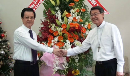 Vice Standing Secretary of the Provincial Party Committee Le Hong Quang presents flowers to the bishop of My Tho diocese Nguyen Van Kham. 