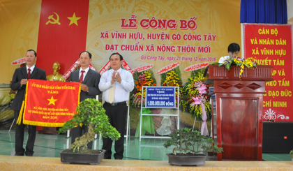 Ông Võ Văn Bình, Phó Bí thư Tỉnh ủy trao Cờ xã Vĩnh Hựu đạt chuẩn quốc gia về xây dựng NTM  cho lãnh đạo xã.