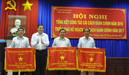 Ông Phạm Văn Tiếu (bìa phải) đại diện UBND huyện Chợ Gạo nhận Cờ thi đua xuất sắc của UBND tỉnh về thực hiện CCHC năm 2016.