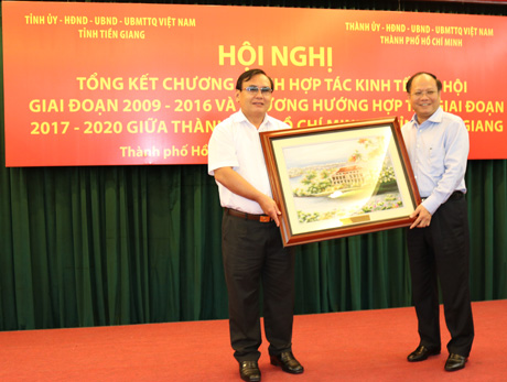 Ông Võ Văn Bình, Phó Bí thư Tỉnh ủy Tiền Giang và ông Tất Thành Cang, Phó Bí thư Thường trực Thành ủy TP. Hồ Chí Minh trao quà lưu niệm giữa hai địa phương.