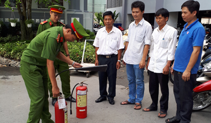 Cán bộ Phòng Cảnh sát PCCC và CNCH hướng dẫn các thao tác sử dụng bình chữa cháy xách tay. 					                                          Ảnh: Thanh Việt