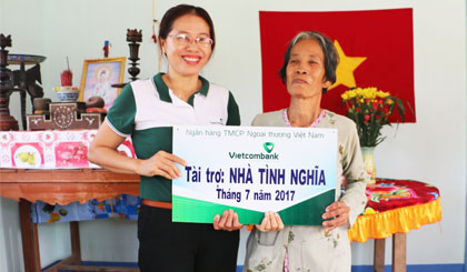Bà Nguyễn Thị Tuyết, Phó Giám đốc phụ trách điều hành Vietcombank Tiền Giang trao bảng tượng trưng cho bà Nguyễn Thị Ghết.