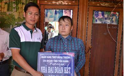 ông Chử Văn Nam, Phó Giám đốc Vietcombank Tiền Giang trao bảng tượng trưng cho gia đình anh Phạm Văn Cường