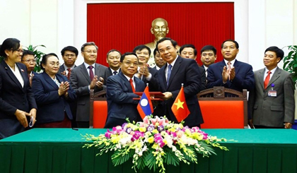 Head of the CPV Central Committee Office Nguyen Van Nen (front, right) and head of the LPRP Central Committee Office Khamphanh Phommathat exchange the signed cooperation agreement (Photo: VNA)