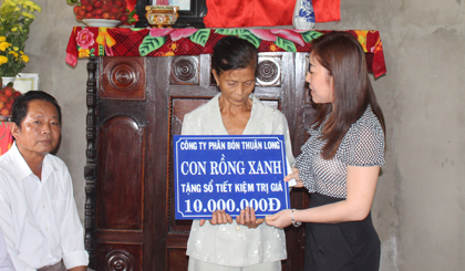 Đại diện Công ty TNHH phân bón Thuận Long tặng sổ tiết kiệm cho gia đình bà Trần Thị Bảy.