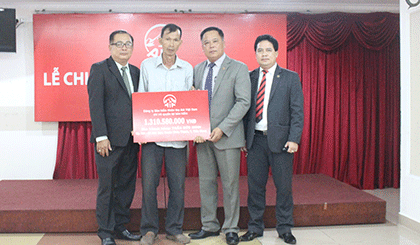 Ông Huỳnh Văn Giàu (bìa trái), Giám đốc kinh doanh văn phòng AIA Tiền Giang 3 trao bảng tượng trưng số tiền hơn 1,3 tỷ đồng cho anh đình anh Minh. 
