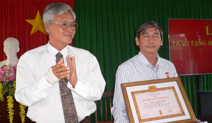Ông Nguyễn Văn Quang, UVTV, Trưởng Ban Tuyên giáo Huyện uỷ trao Huy hiệu 30 năm cho ông Nguyễn Văn Chính ( TT. BDCT huyện