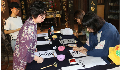 Du khách trải nghiệm viết thư pháp với sự hướng dẫn của người Nhật Bản tại lễ hội