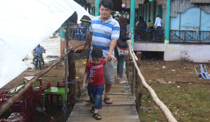 Du khách đi trên cầu nối Nhà hàng Hương Biển để tránh bị sóng đánh ướt.