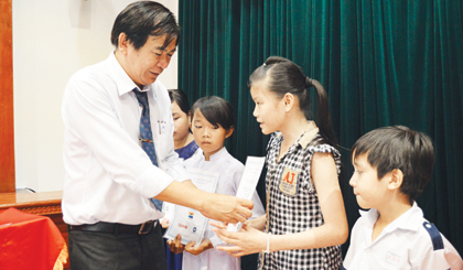 Đồng chí Nguyễn Minh Tân trao học bổng cho các em học sinh.
