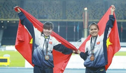  Pham Thi Hue (L) and Pham Thi Hong Le celebrate with the national flag after winning the women’s 5,000m event of the Singapore Open Track and Field Championship (Photo: zing.vn)
