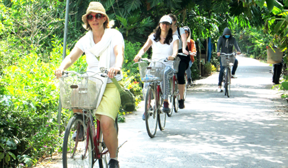 Du khách đi xe đạp để tham quan các công trình kiến trúc, cuộc sống của người dân ở Làng cổ Đông Hòa Hiệp (huyện Cái Bè).