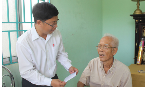 Bí thư Huyện ủy Cái Bè Trần Thanh Nguyên tặng quà cho ông Nguyễn Văn Thuần (thương binh 71%), ngụ ấp Hòa. 