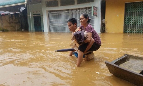 A traffic police in Thanh Hoa helps a local move to a safer place amidst serious floods affecting the province (Photo: VNA)