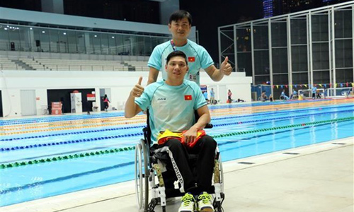 Swimmer Vo Thanh Tung (on wheelchair) and his coach after the men's 50m freestyle S5 event on October 11 (Photo: VNA)  