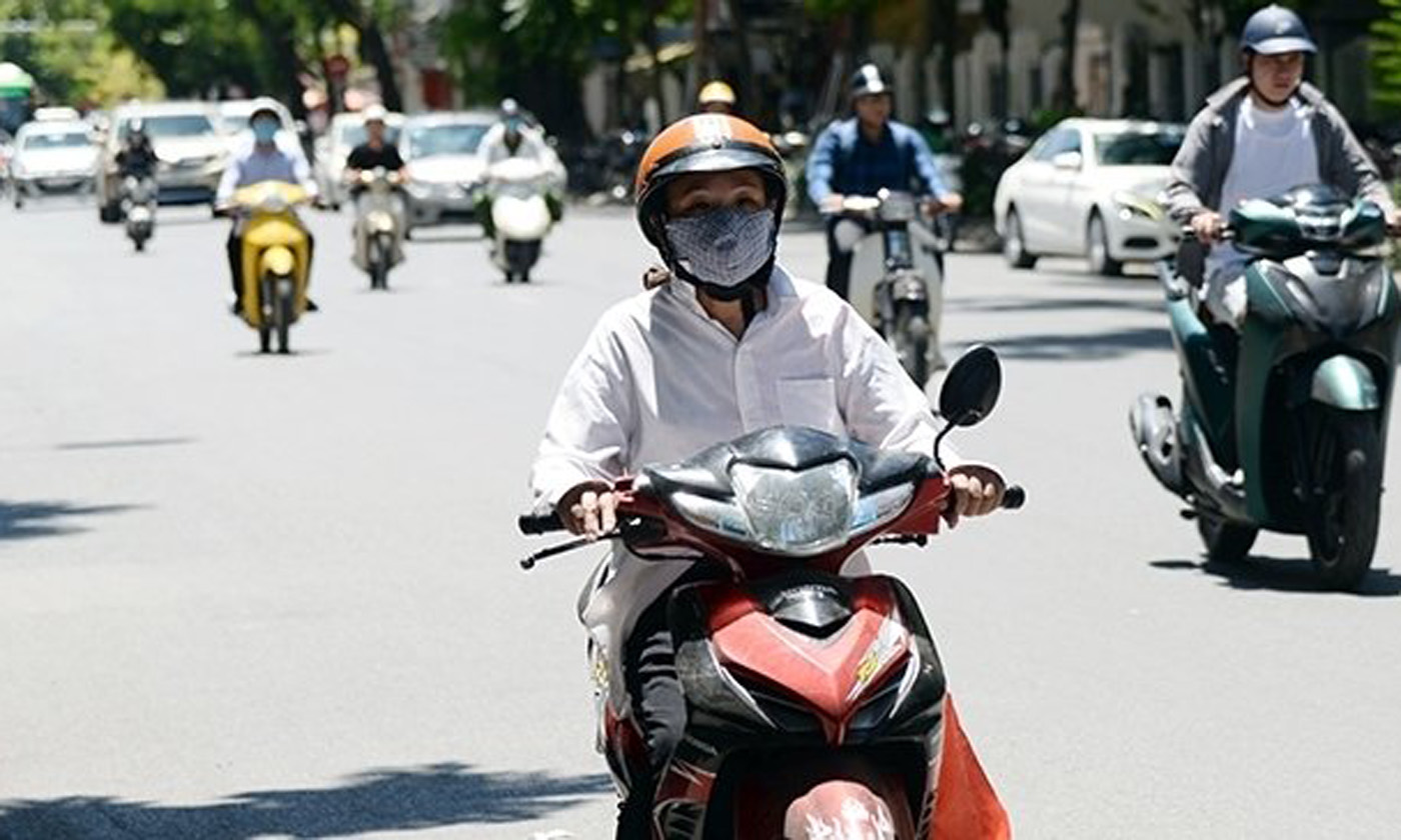 Hanoians cover against the extreme heat while in traffic. (Photo: NDO/My Ha)