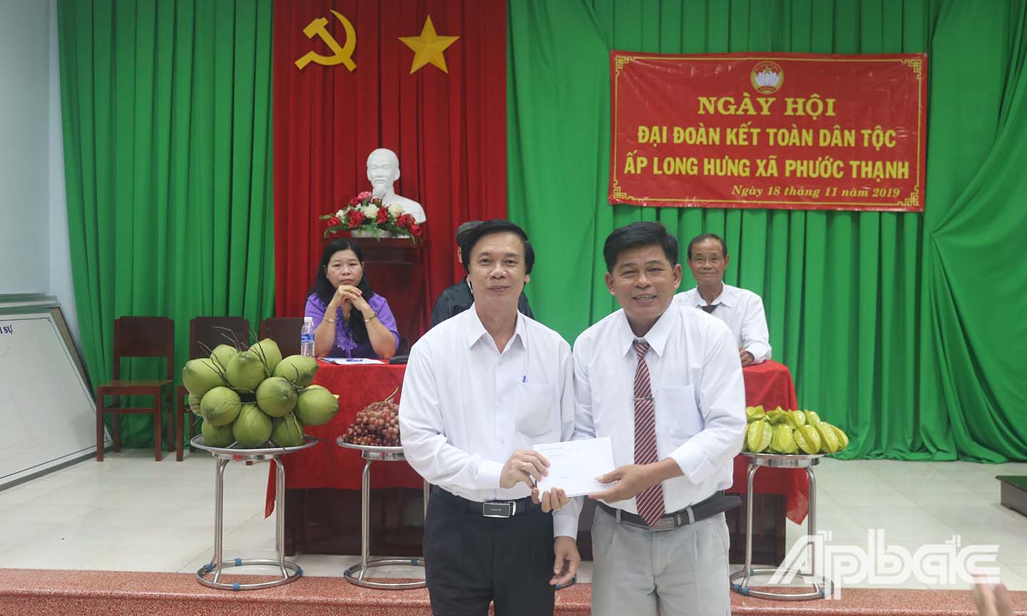 Đồng chí Nguyễn Văn Danh (hàng đầu, bên trái) trao các phần quà cho đại diễn Ban Quản lý ấp Long Hưng, xã Phước Thạnh, TP. Mỹ Tho.