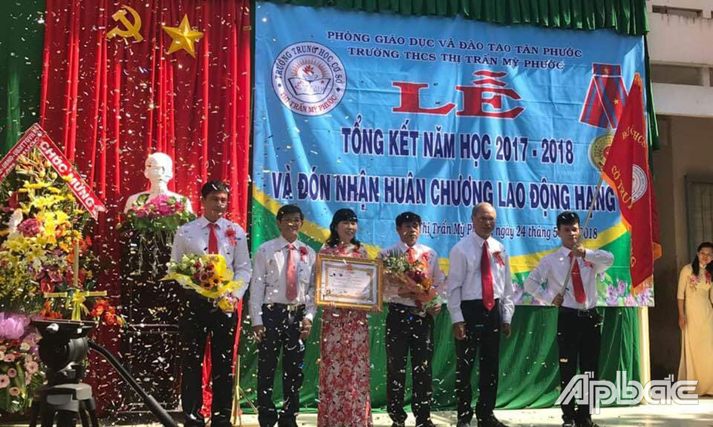 Cô Loan cùng Ban Giám hiệu Trường THCS thị trấn Mỹ Phước đón nhận Huân chương Lao động hạng Ba tại Lễ tổng kết năm học 2017 - 2018. 