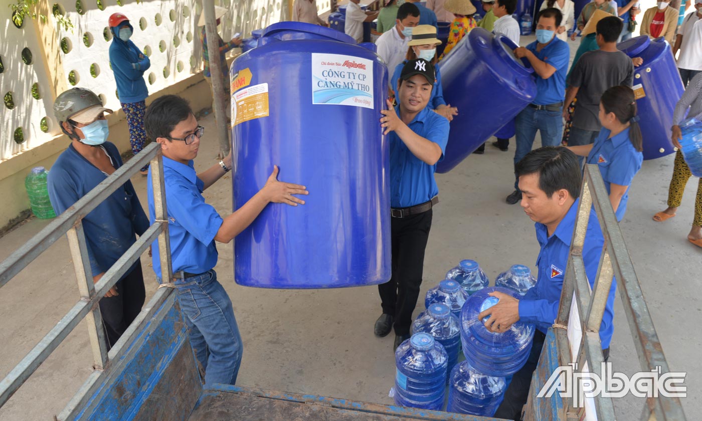 Đoàn viên Báo Ấp Bắc hỗ trợ người dân xã Tân Thạnh (huyện Tân Phú Đông) vận chuyển bồn nước về nhà.