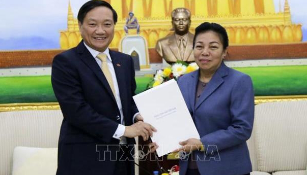 Vietnamese Ambassador to Vietnam Nguyen Ba Hung (L) conveys a letter of congratulations from the CPV Central Committee to the LPRP Central Committee, via Sounthone Sayachak, head of the LPRP Central Committee’s Commission for External Relations, on March 19. (Photo: VNA)