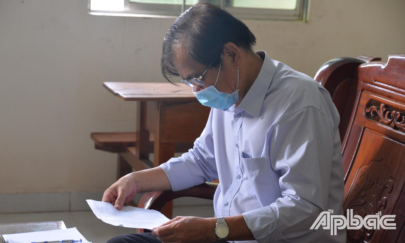 Đồng chí Nguyễn Minh Tân kiểm tra danh sách các trường hợp đang bị cách ly tại nhà trên địa bàn huyện Chợ Gạo..