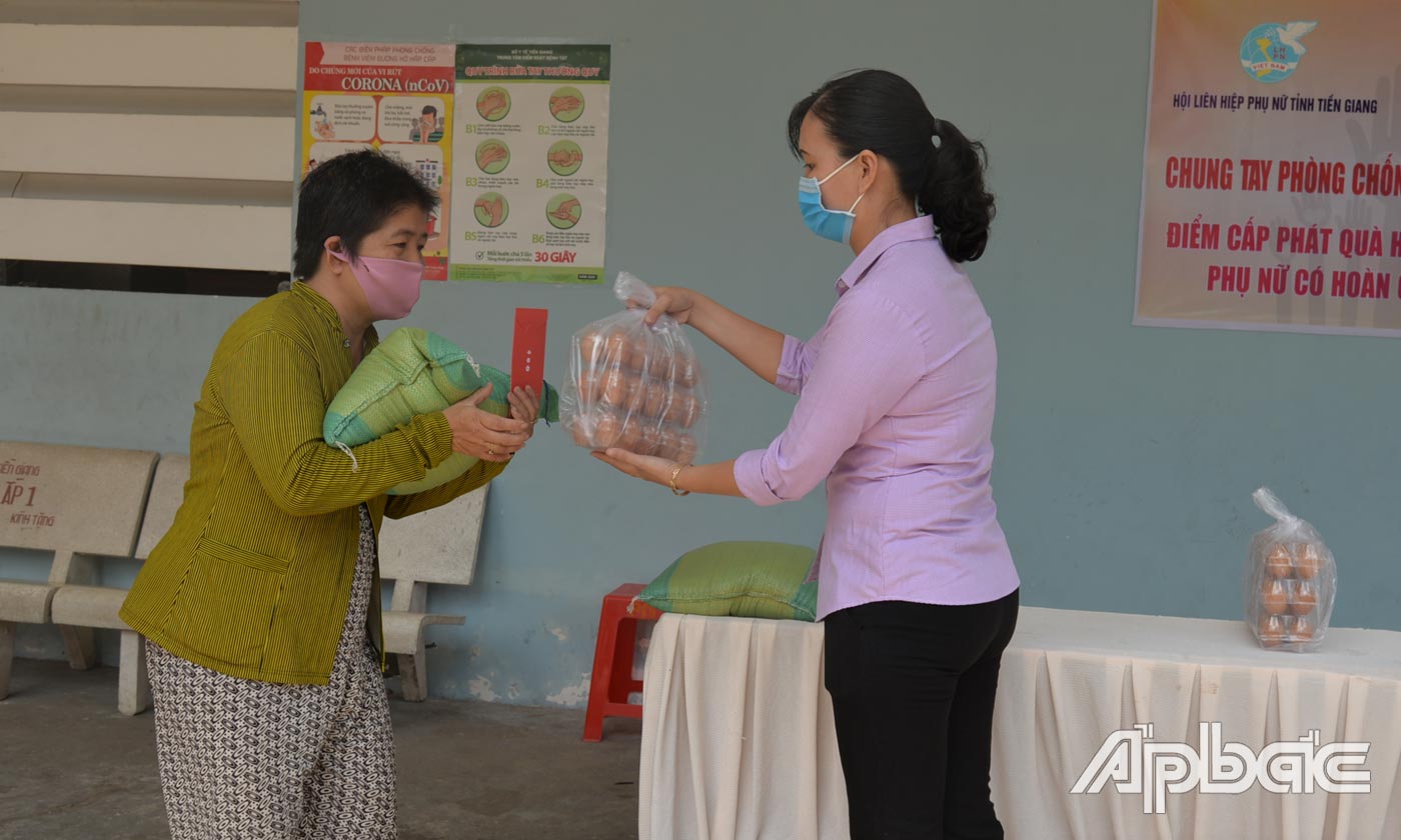 Chủ tịch Hội LHPN tỉnh Nguyễn Thị Kim Phượng phát quà cho phụ nữ nghèo, bán vé số.