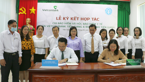 Bà Nguyễn Thị Tuyết, Giám đốc Vietcombank Tiền Giang cùng ông Võ Khánh Bình, Giám đốc BHXH tỉnh Tiền Giang thực hiện ký thoả thuận hợp tác chi BHXH, BHYT.