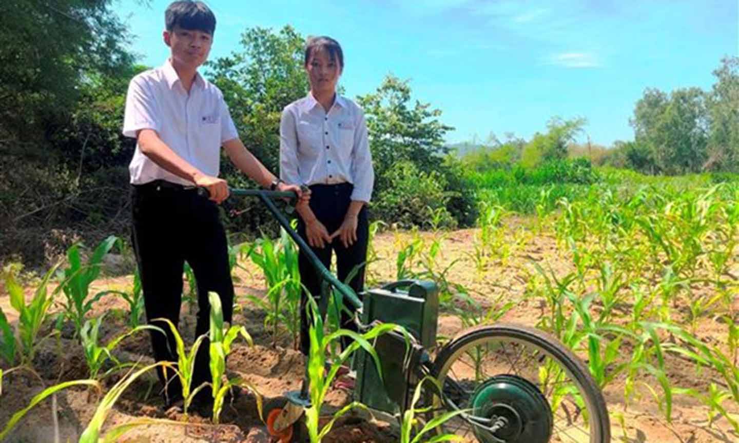 Em Phạm Thị Hoài Phương và Lê Tuấn Kiệt với máy cày điện để làm cỏ, bón phân. (Ảnh: Nguyên Linh/TTXVN)