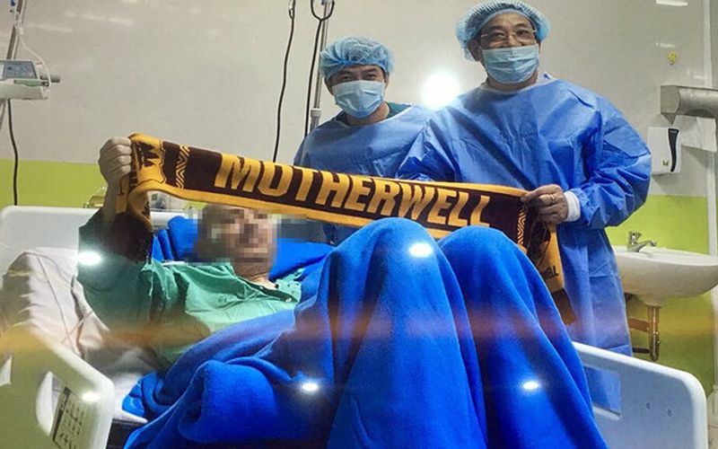  The British pilot holds out a scarf with the word ‘Motherwell’, name of his favorite football club, on it. Photo: Cho Ray Hospital